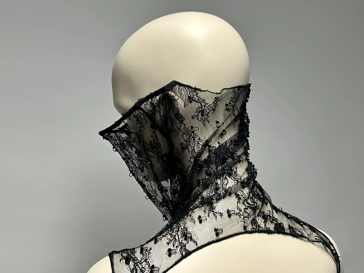 Mannequin de dos. Le body en dentelle noir posé sur les épaules laisse apparaitre un dos nu. La pièce remonte jusqu'au mileu du crane et passe devant les oreilles.